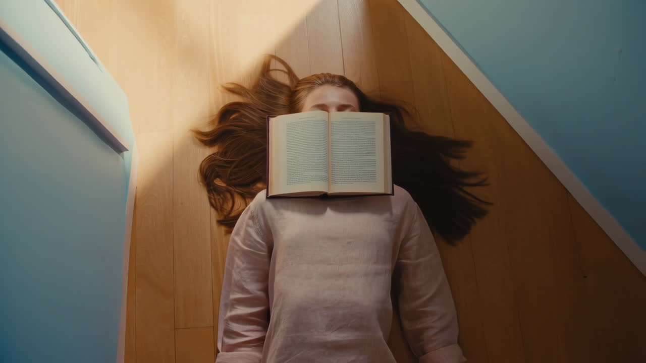 Person lying on the floor with a book covering their face