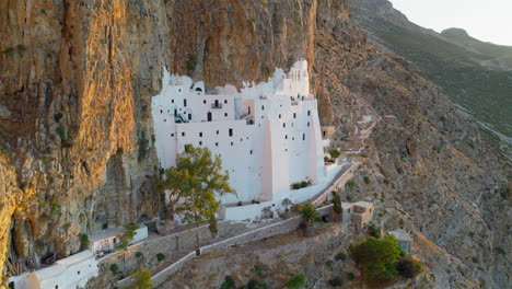 panagia hozoviotissa monastery illuminated by morning sunlight on cliffs of amorgos island, greece