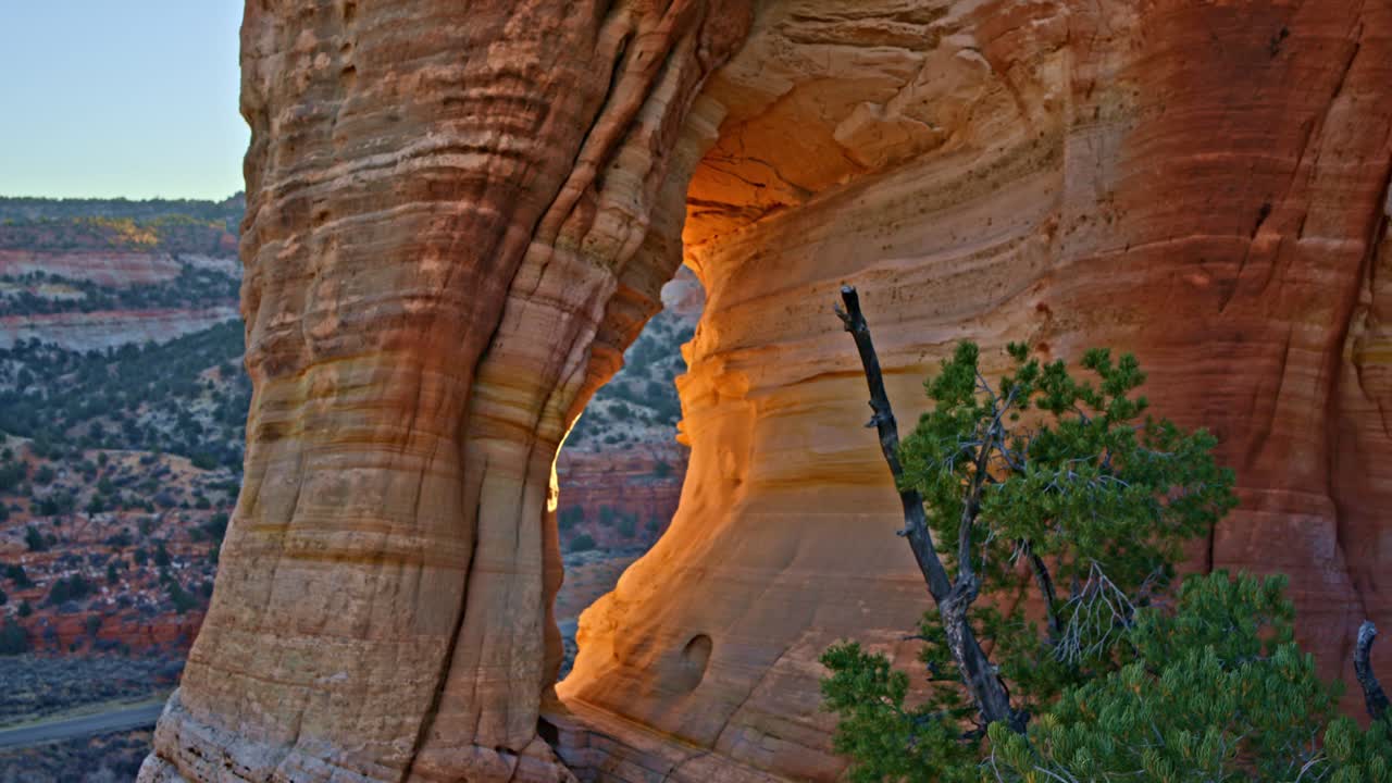 Cinematic drone shot soaring over a sandstone arch as the sun rises near Kanab, Utah.
