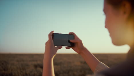 girl taking field picture at countryside. female hands hold smartphone closeup.