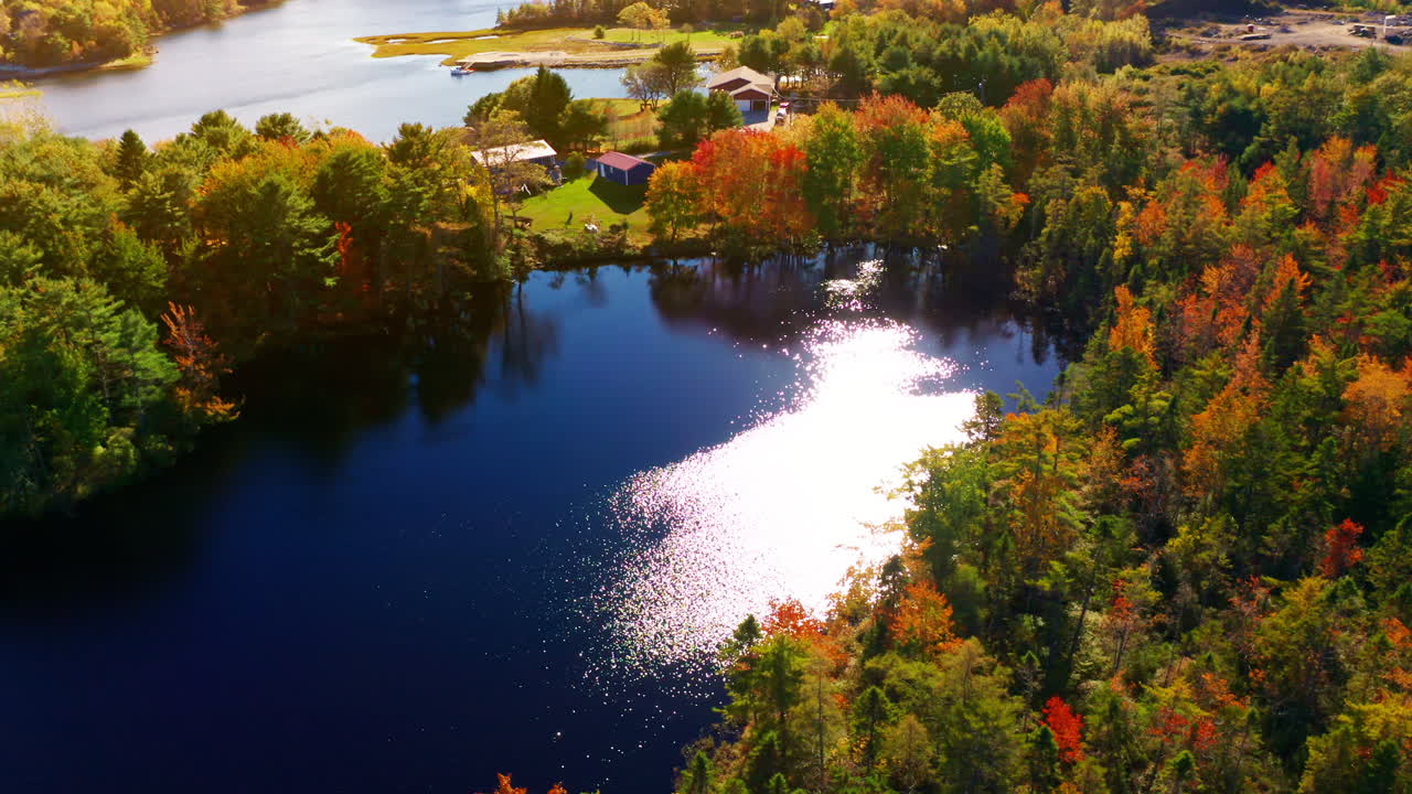 Aerial drone shot over the coastline of Oak Island, Nova Scotia, Canada.
High view of the sea, autumn colorful trees foliage. Picturesque landscape. Fall vibrant colors.