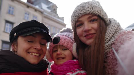 lesbian couple tourists with adoption child girl taking selfie or making video chat on city street