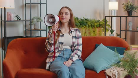 young woman shout in megaphone loudspeaker announces discounts sale of real estate at home on sofa