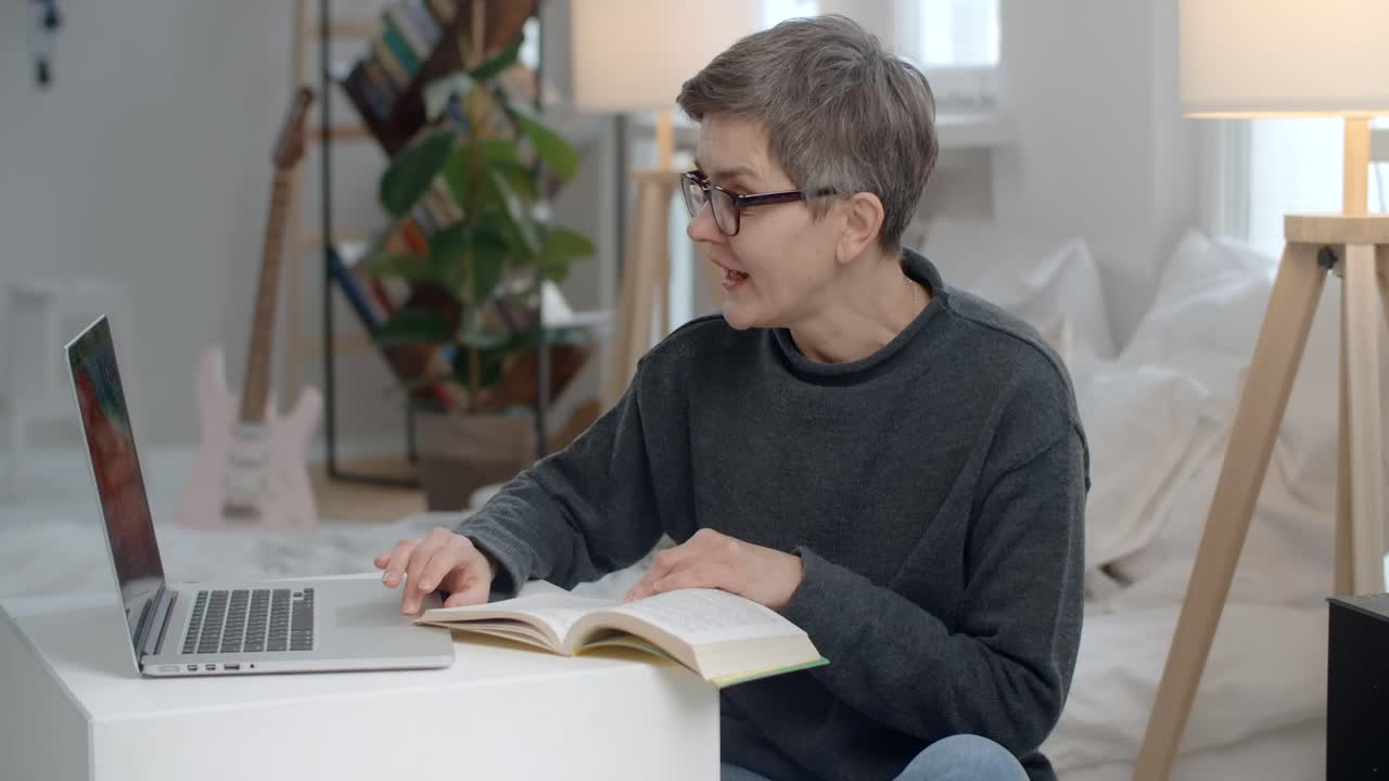 Woman working from home, reading and using laptop
