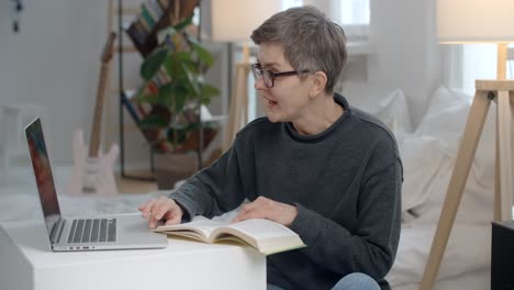 woman working from home, reading and using laptop