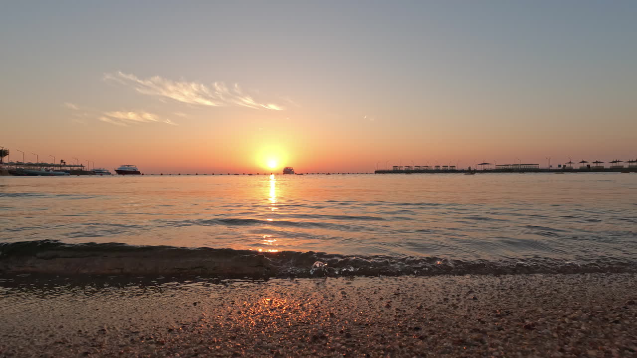 일몰이 다채로운 수평선을 만드는 동안 해변에서 움직이는 작은 maves