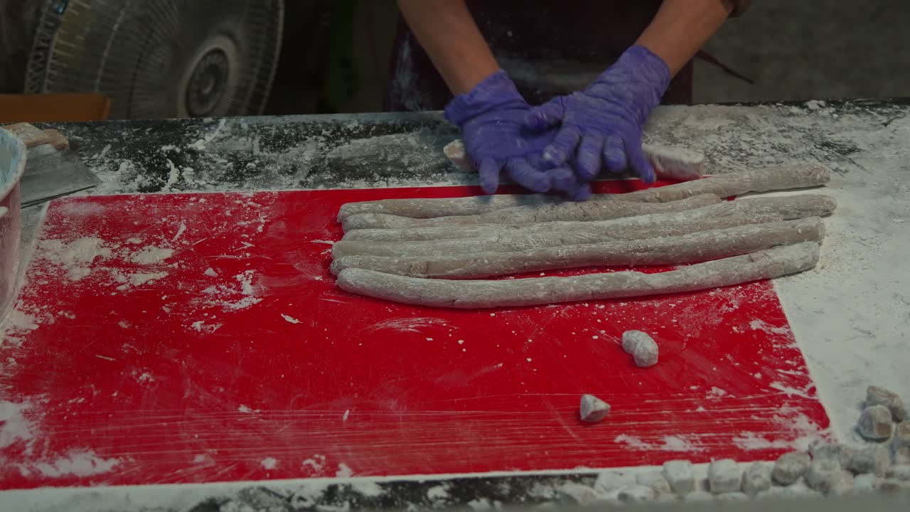 Venditore di mercato notturno che prepara da zero il popolare dessert a base di palline di taro, arrotolando a mano l'impasto di taro in forme cilindriche, ripresa ravvicinata
