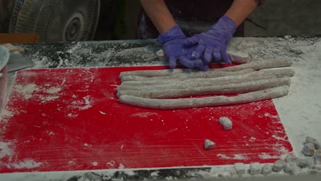 Vendedor-Del-Mercado-Nocturno-Preparando-El-Popular-Postre-De-Bolas-De-Taro-Desde-Cero,-Enrollando-A-Mano-La-Masa-De-Taro-En-Formas-Cilíndricas,-Primer-Plano