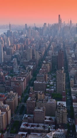 Vast New York panorama at sun down. Park with a pond in the downtown. Metropolis at backdrop of pink skies. Vertical video