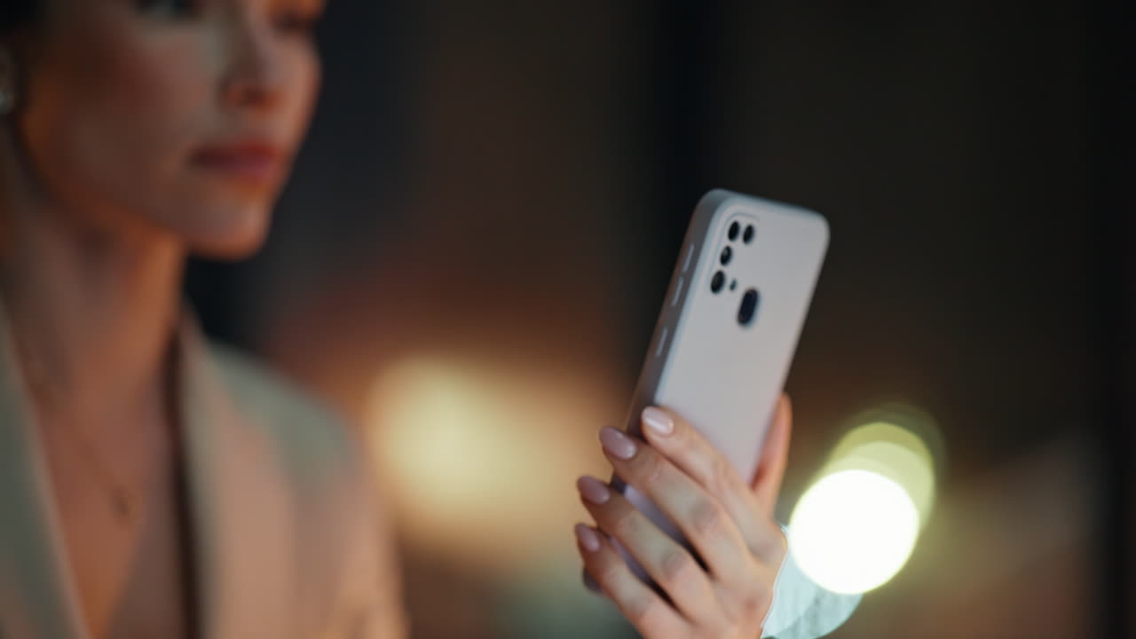 Hand using cell night office. Closeup businesswoman watching mobile phone video