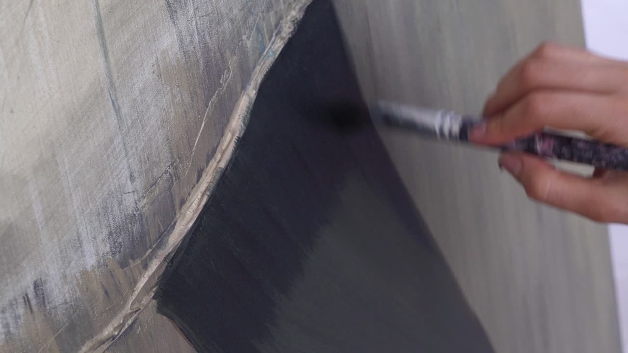 mano de artista sosteniendo pincel y pintando sobre lienzo en vista cercana