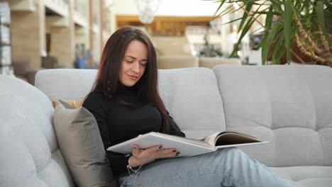 a woman sits comfortably on a soft elegant sofa in a stylish furniture showroom a woman sits comfortably on a soft elegant sofa in a stylish furniture showroom attentively browsing a magazine with modern sofa designs