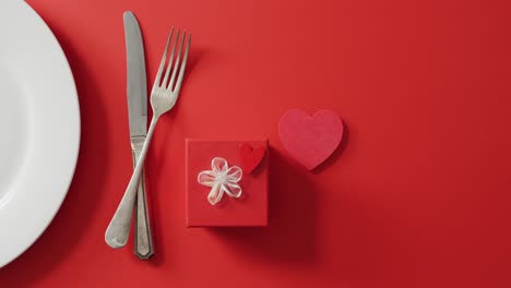 Teller-Und-Besteck-Mit-Geschenk-Auf-Rotem-Hintergrund-Am-Valentinstag