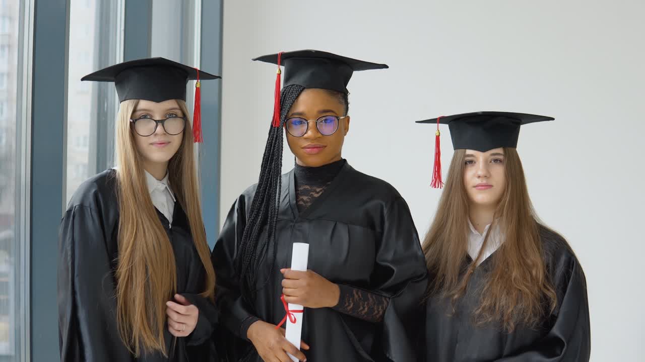 tres estudiantes femeninas de diferentes razas con un diploma en la mano. educación superior en el extranjero. tres estudiantes de diferentes nacionalidades