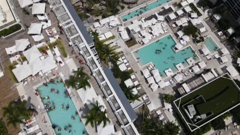 Piscina-En-La-Azotea-Con-Los-Huéspedes-Del-Hotel-En-Miami-Beach-Frente-A-La-Playa-Del-Océano-Azul-Al-Mediodía-Con-Muchas-Sombrillas-En-La-Playa-South-Beach,-Florida