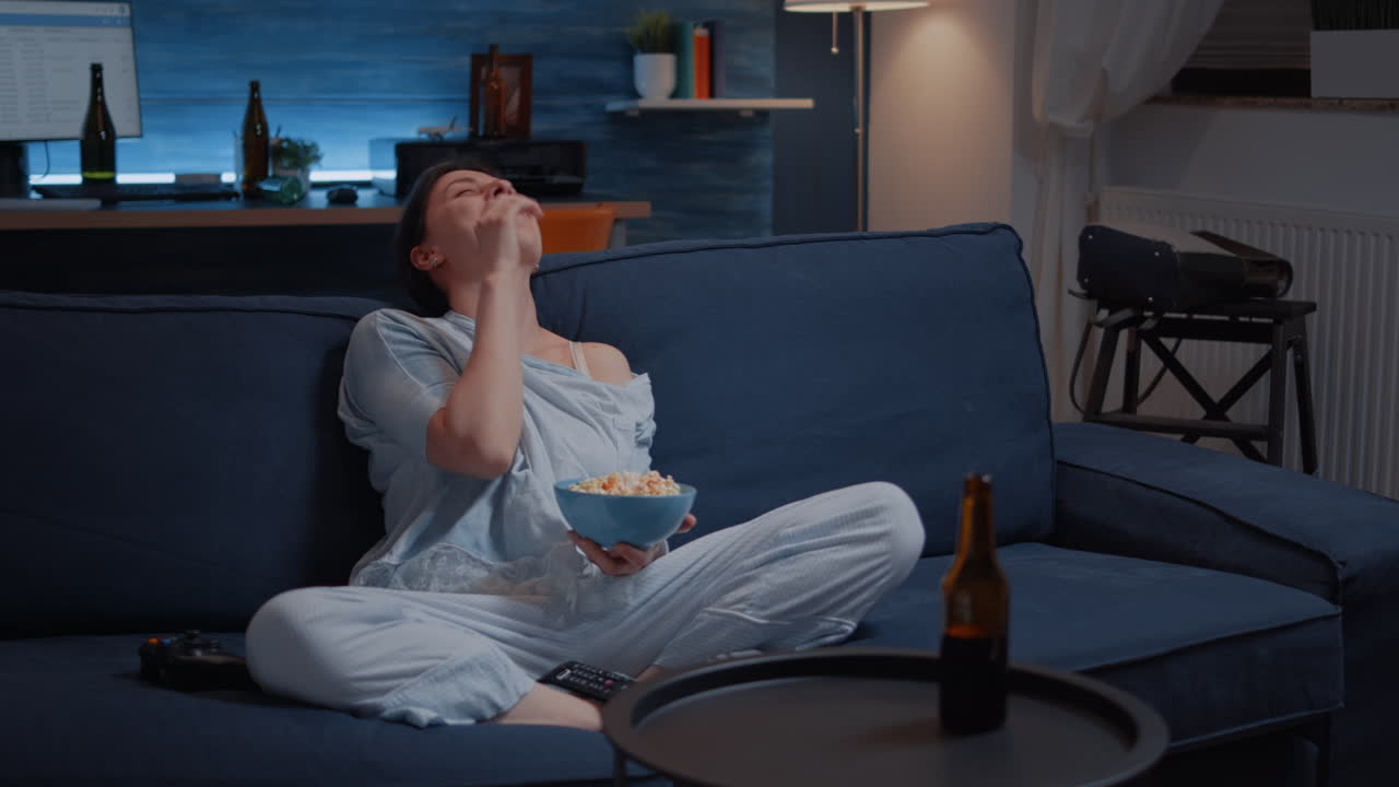 Relax woman in pajamas eating popcorn watching TV,