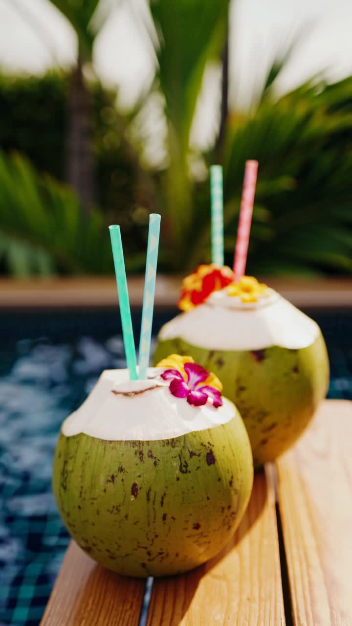 Tropical video concept with two coconuts adorned with flowers and straws, shot from a low angle, set