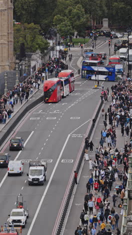 traffic and people crossing westminster bridge next to the houses of parliament, london, uk in vertical