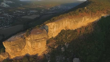 aerial view of a dramatic cliff face in a valley at sunset