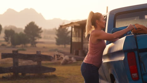 Portrait-Of-Woman-Unloading-Backpacks-From-Pick-Up-Truck-On-Road-Trip-To-Cabin-In-Countryside