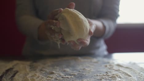 mujer terminando de hacer masa redondeada de pizza y mostrando a la cámara