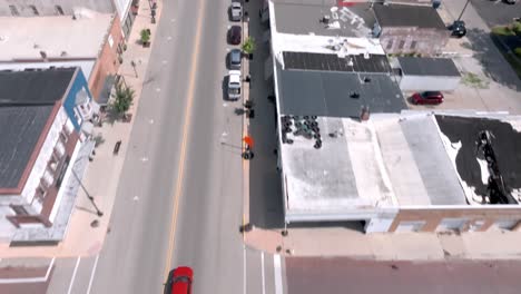 Downtown-Geneseo,-Illinois-with-drone-video-following-cars-overhead-and-tilting-up-to-reveal-city