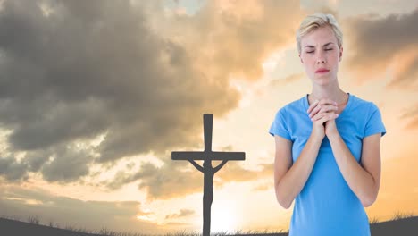 Animation-of-caucasian-woman-praying-and-crucifix-at-sunset