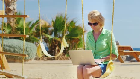 Frau-Sitzt-Auf-Einer-Schaukel-Und-Benutzt-Einen-Laptop