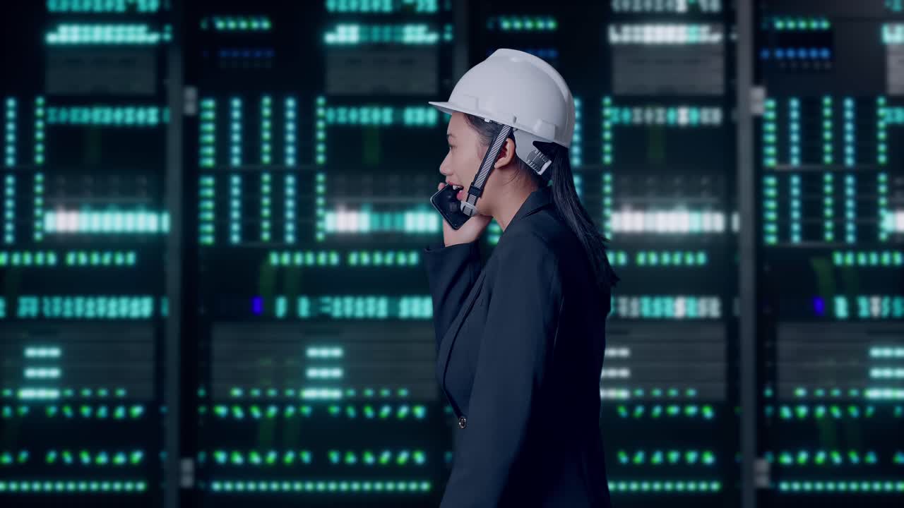 Side View of Asian Businesswoman Talking On Smartphone While Walking in Server Room Data Center