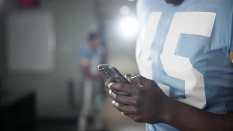 football player texting in locker room