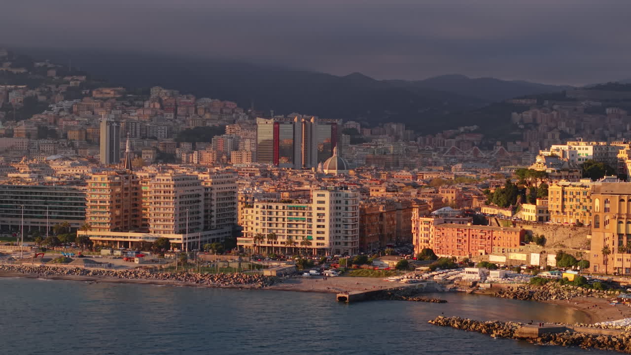 Ripresa panoramica con drone di Genova all'alba con città e montagne