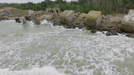 aerial establishing view of abandoned seaside fortification buildings at karosta northern forts, baltic sea coast , large waves, overcast day, slow motion, drone shot moving forward