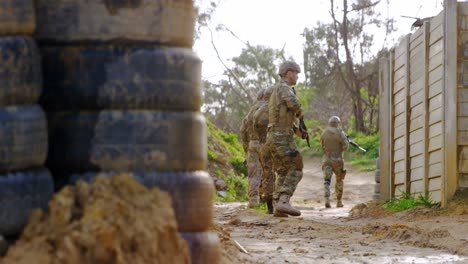 Vista-Frontal-Del-Soldado-Militar-Caucásico-Caminando-Con-Rifle-Durante-El-Entrenamiento-4k