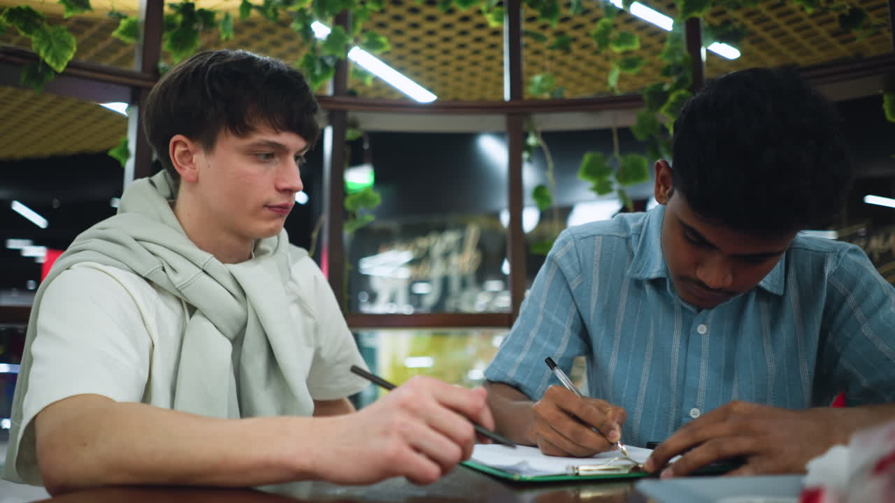 Close view of colleagues holding pen over document, fingers poised mid scribble, focus on hands and paper filled with notes, soft office background blur, warm natural light captures focused teamwork