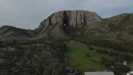 casa de campo con campos verdes al pie de la montaña torghatten en la isla torget en bronnoy, nordland, noruega