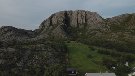 farm house with green fields on foothill of torghatten mountain in torget island in bronnoy, nordland, norway