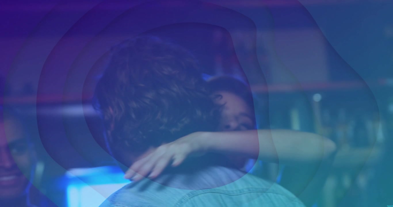 Uomo in jeans che riceve un abbraccio di saluto dopo un batticinque in un club, luce blu che pulsa sulla spalla.