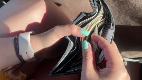 GIRL-HANDS-COUNTS-MONEY-BILLS-INSIDE-A-WALLET