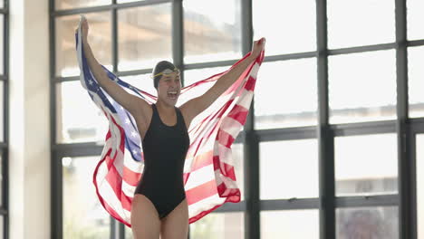 celebrating victory, female swimmer holding american flag in indoor pool area
