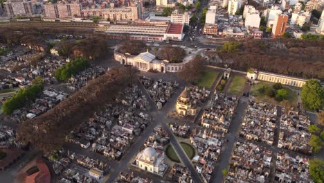 aerial shot showing entrance of chacarita cemetery with church and skyscraper building of buenos aires skyline in background