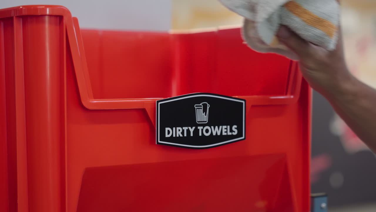 Man Put The Used Towels Inside The Bucket With Dirty Towels Label In The Gym. - closeup shot