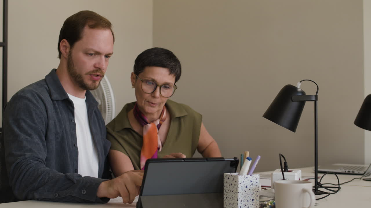 Two Colleagues Collaborating on a Tablet in an Office