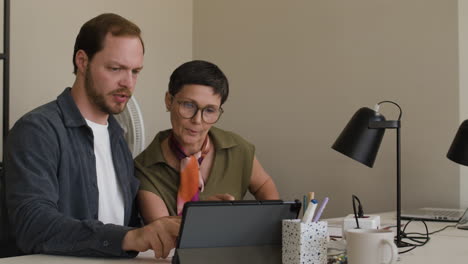 two colleagues collaborating on a tablet in an office