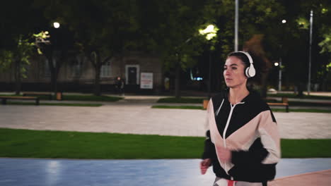 Sportliche-Sportlerin-Mit-Bluetooth-Kopfhörern,-Die-Nachts-Im-Park-Läuft-2
