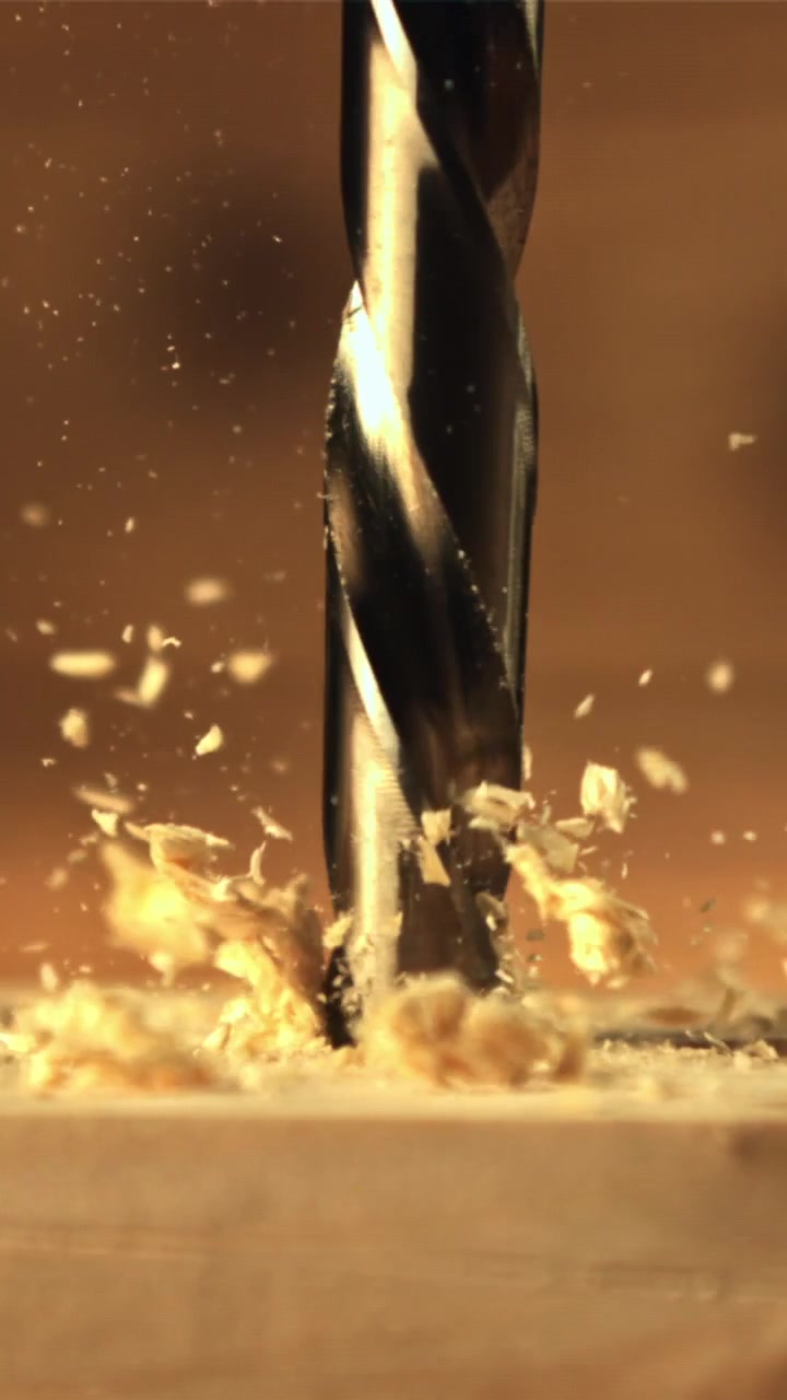 Punta da trapano che penetra nel legno al rallentatore con trucioli volanti