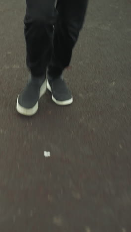 close up leg view of two individuals wearing joggers and sneakers, walking on a track near a grassy field before transitioning into a jogging pace