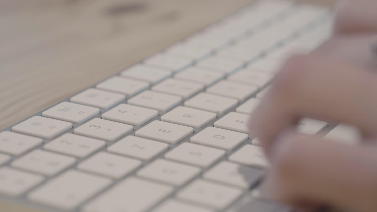 Detail shot of fingers typing on a white wireless keyboard. Minimalist workspace setting focused on productivity, writing emails, or software development on a modern device
