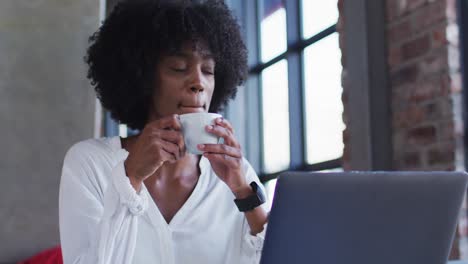 Glückliche-Afroamerikanische-Frau-Sitzt-Im-Café,-Trinkt-Eine-Tasse-Kaffee-Und-Lächelt