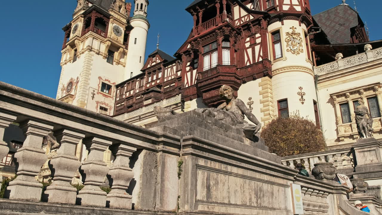 View of a sculpture at The Peles Castle in Romania. Castle on the background, tourists