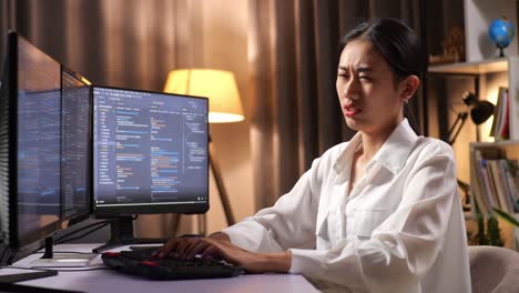 asian woman programmer having a backache while creating software engineer developing app, program, video game on desktop computer at home. terminal with coding language